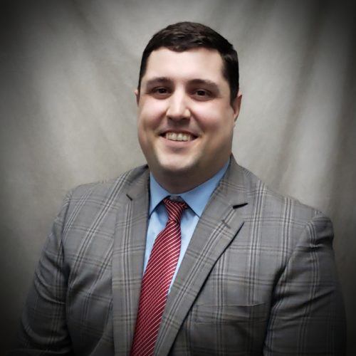 a man wearing a suit and tie smiling at the camera