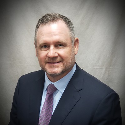 a man wearing a suit and tie smiling at the camera