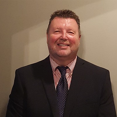 a man wearing a suit and tie smiling at the camera