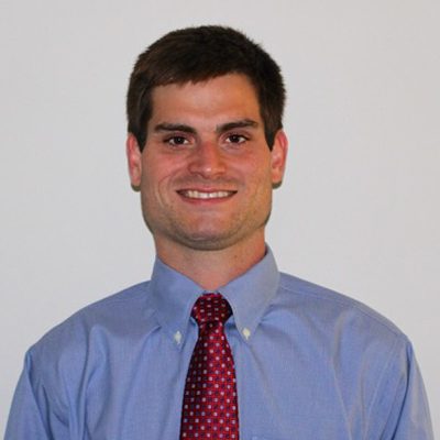 a man wearing a suit and tie smiling at the camera