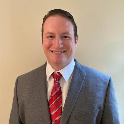 a man wearing a suit and tie smiling at the camera